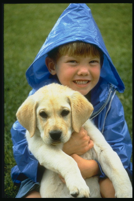 Мальчик в синем дождевике со щенком на руках
