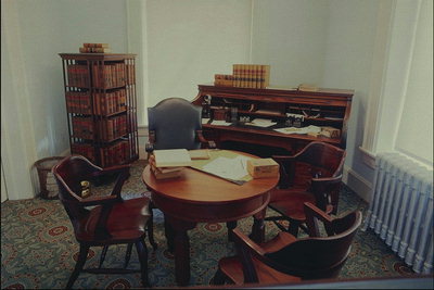 Офис. Круглый стол, кресло, деревянные стулья, шкаф для книг и документов
