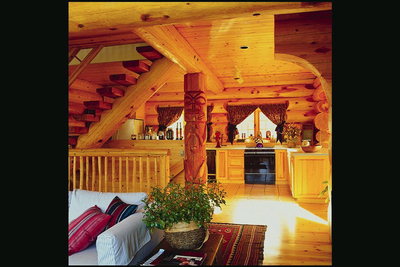 Комната из дерева. Лестница, колоны с рисунками, мебель, теплый тон материала