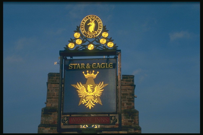 Signboard on a stone wall. Picture an eagle and stars, figure in the golden tone