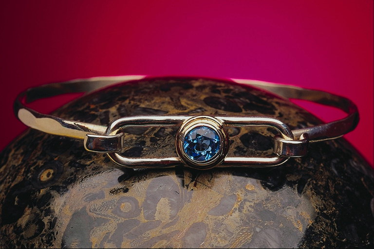Armband, um einen Bogen und einen dünnen blauen Stein in der Mitte