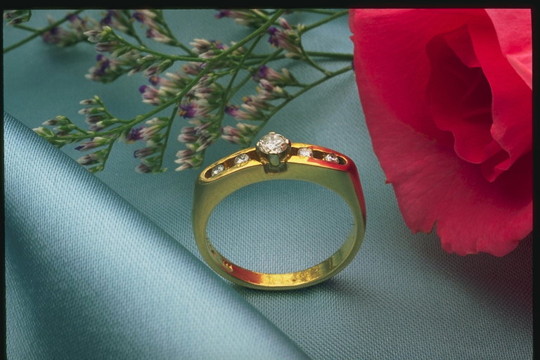 Prsten s diamanty v blízkosti tmavě-růžovou růží