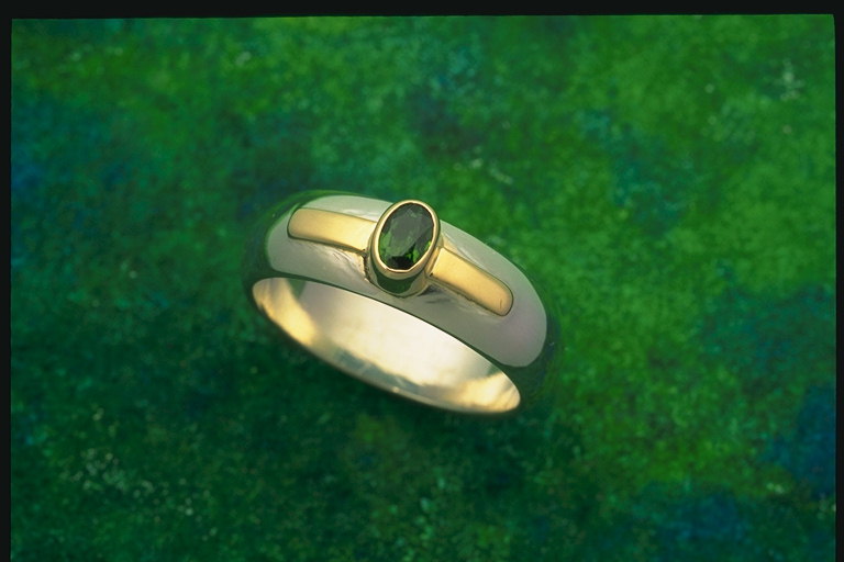 Den brede form af en ring med en lille sten af en mørk-grønne