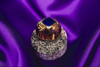 Ring in gold with the waves and the dark-blue stone in the form of diamond