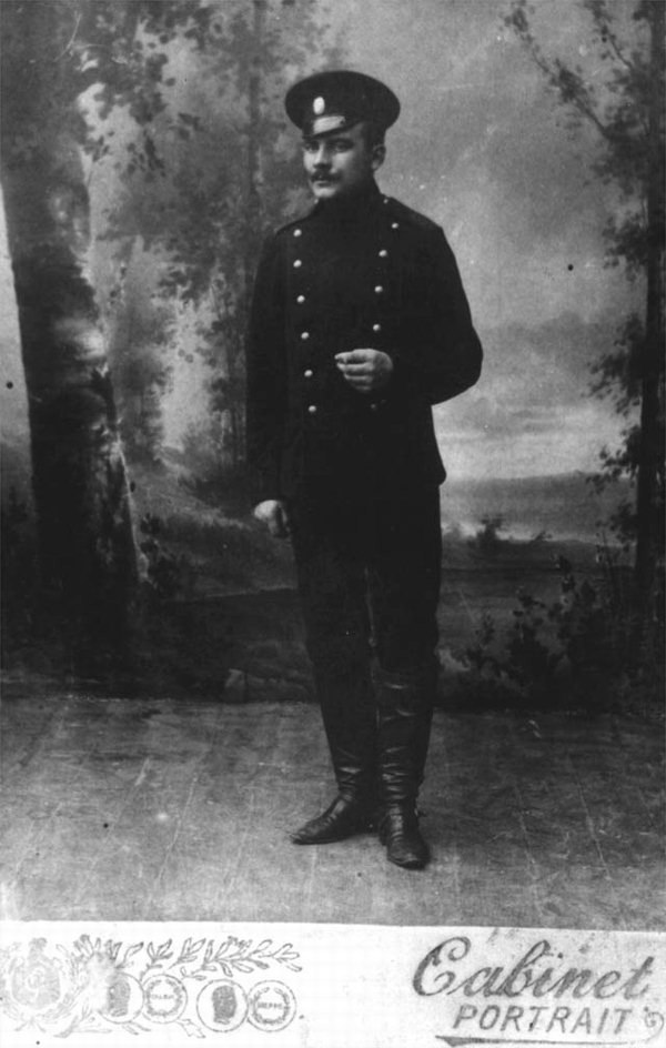  Молодой офицер в офицерской фуражке на фоне живописной картины