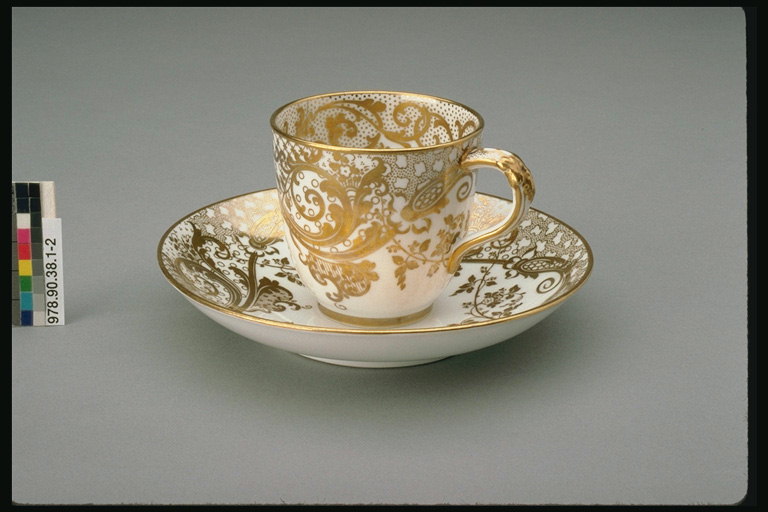 A cup and saucer in the golden-colored illustrations. Branches and grid