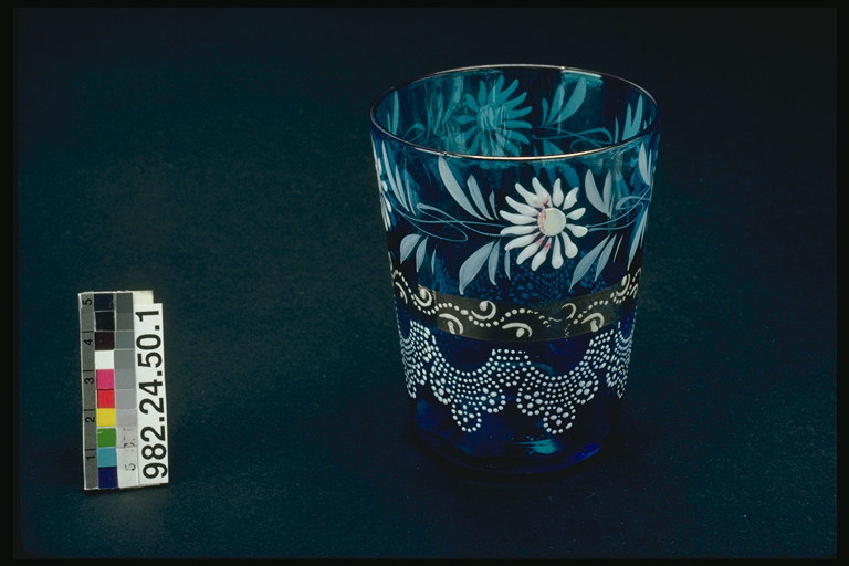 Glass with blue glass. White daisies and brown twigs