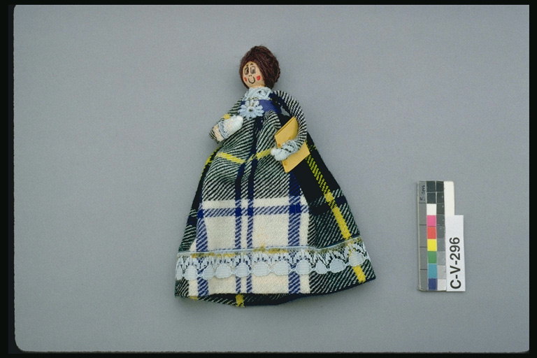 A boneca com um tecido. Vestido em uma gaiola de cinza, branco e cores