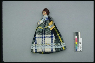 Doll med vev. Kjole i et bur av grå, hvite og gule farger