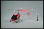 Un helicòpter de color vermell amb rodes en moviment i fulles