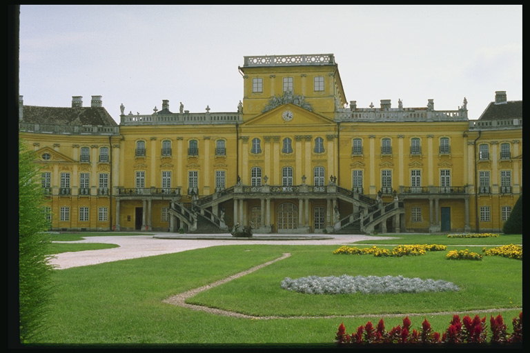 The palace with columns. Lawns with yellow flowers