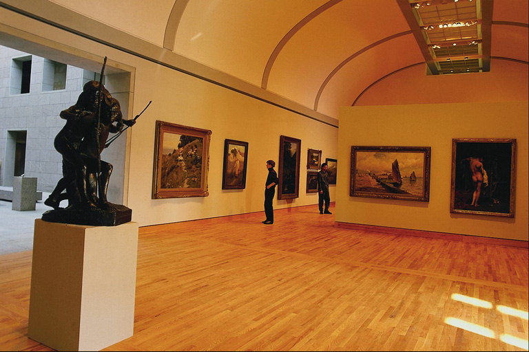 Una de les sales de museu, amb parquet de fusta, pintures i exposicions