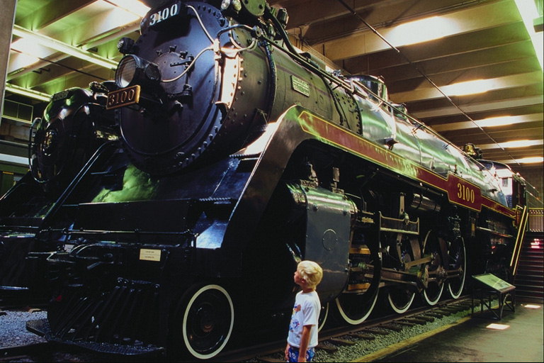 O garoto ao lado de uma locomotiva exibem