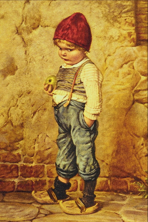 A fiú kék nadrágot húzni, egy nagy zöld alma a kezében