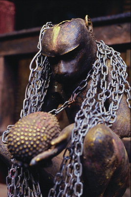 Statuja. Monkey prickly augļu viņu rokās. Metāla ķēdes