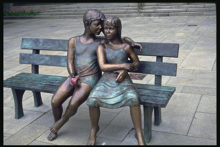 Sastāvā, kas bronzas. Zēns un meitene sēdes par sols