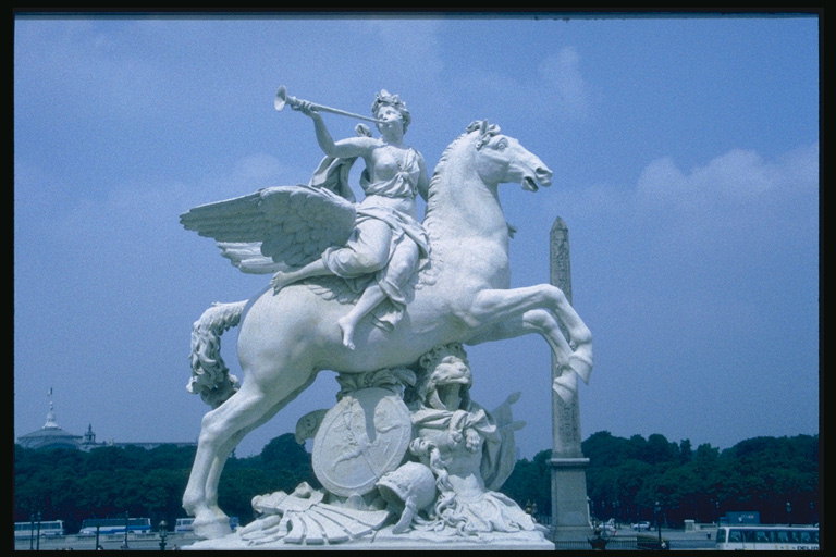 Skulptur. Angel på en häst med en pipa i händerna på