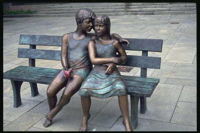 Kompozicija iš bronzos. Berniukas ir mergaitė sėdi ant stendo