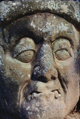 Каменная голова пожилого человека с зубами - клыками