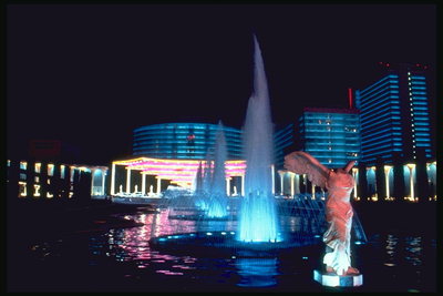 Фонтан с синей водой в ночном Лас-Вегасе. Статуя женщины с крыльями