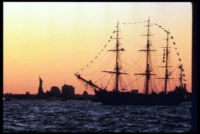 Корабль в порту Нью-Йорке на фоне статуи свободы и вечернего заката