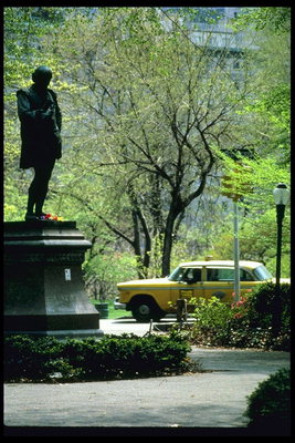 Фото жёлтого такси в Нью-Йорке. Статуя человека в парке