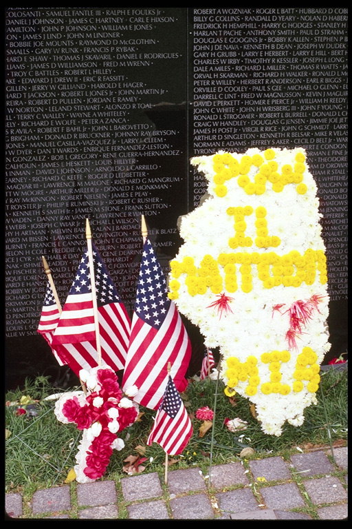 Американские флаги и цветы у памятной стены