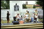 Группа музыкантов играют на музыкальных инструментах перед памятником