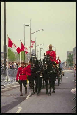 Кортеж королевы Британии в сопровождении верховой полиции. Вдоль дороги развешаны флаги Канады