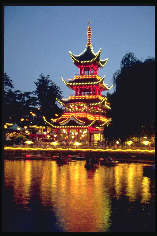 Здание китайской культуры стоит на берегу реки освещённая фонарями