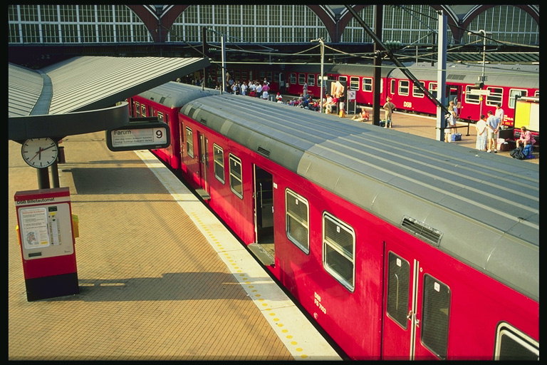 Поезд с розовыми вагонами стоит на вокзале 