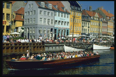 Группы людей стоят на мосту у реки. Люди катаются на лодке