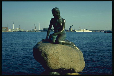 Скульптура русалки сидящей на камне и смотрящей в даль моря