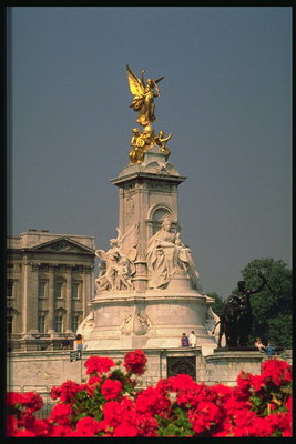 Статуя в золотистом тоне. Скульптуры с гипса. Красные цветы