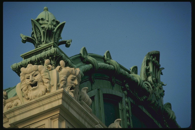 Здание со скульптурами. Рычащие головы на вершине колоны