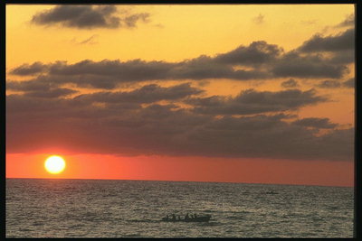 Vivid zonsondergang op zee. Vissersboot loopt naar de plaats van de visserij