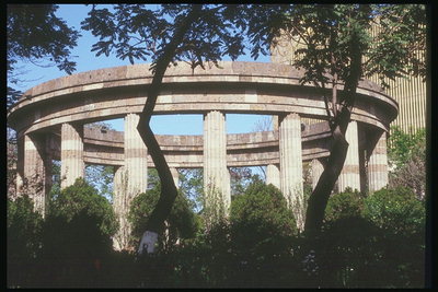 Колоннада поддерживающая круглое сооружение в зелёном массиве города
