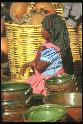 Женщина на рынке торгует посудой. Южное солнце изматывает продавщицу