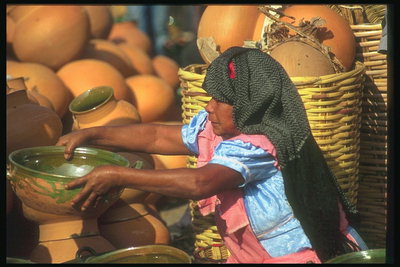 Женщина демонстрирует потенциальному покупателю свою посуду из глины