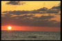 Яскравий захід сонця на морі. Рибальський човен курсує до місця лову риби