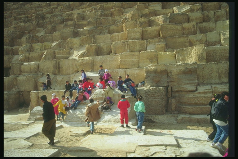 Каменные блоки подножия пирамиды. Туристы пустыни 