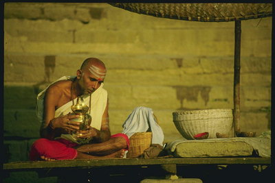 Монах сидящий на столе со скрещенными ногами с вазой в руке