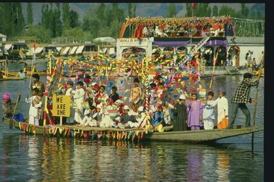 Люди плывущие по реке в праздничных костюмах. Ярко украшенная лодка