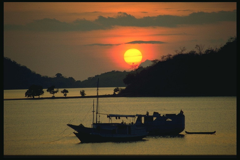 Закат солнца. Две лодки стоят недалеко от берега в море