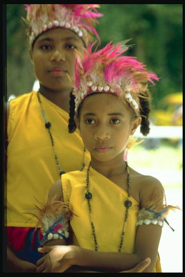 Две девочки в жёлтых костюмах и перьями на голове