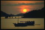 Закат солнца. Две лодки стоят недалеко от берега в море