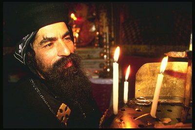 Человек молящийся в храме у алтаря со свечами
