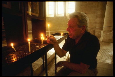 Мужчина в соборе ставит свечку у алтаря