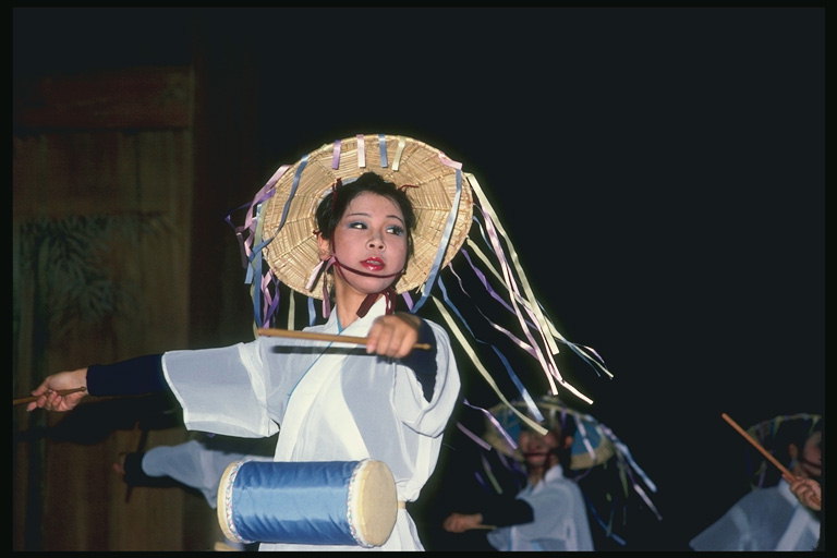 Японская женщина в соломенной шляпе играет на барабане