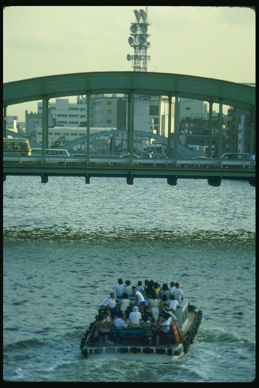 Люди плывут в лодке по городской реке